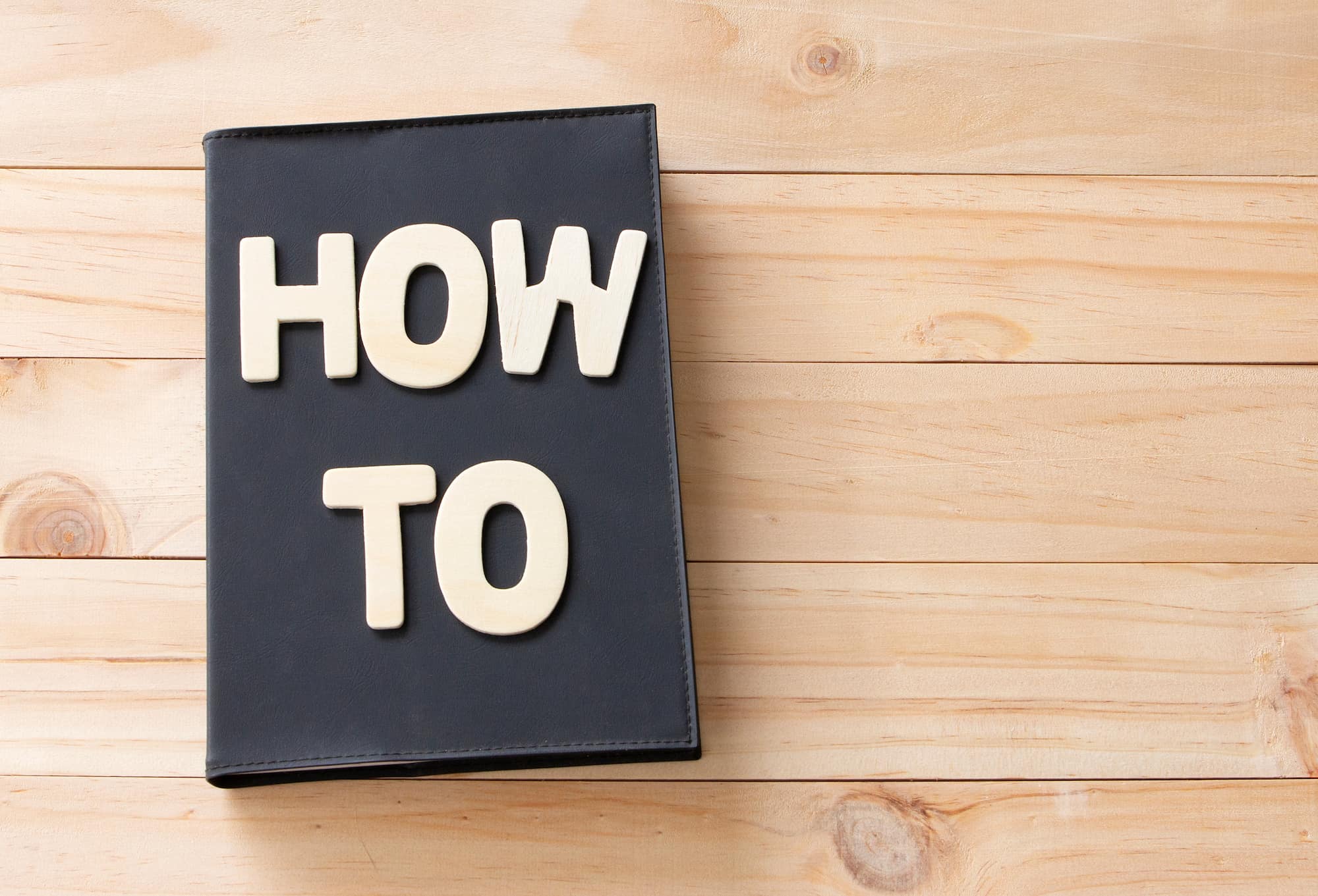 そのまま？更地？空き家の売却手法を選ぶ際の注意点のイメージ　HOW TOと書かれた本が机に置いてある