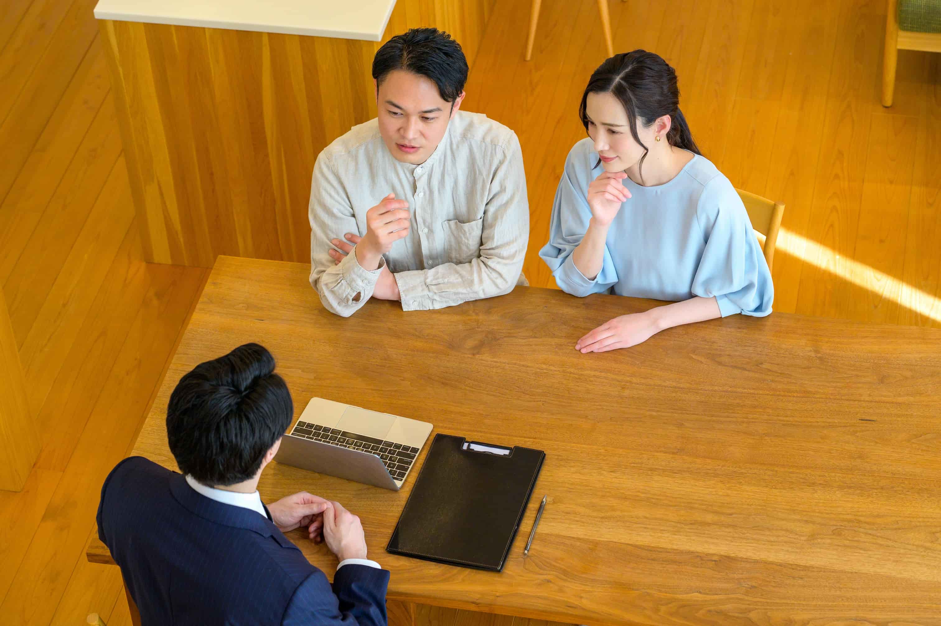 信頼できる買取業者の選び方のイメージ　不動産会社の担当者と夫婦が話し合いをしている様子